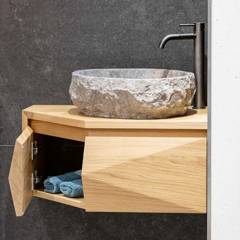 Das Möbel aus massiver Eiche bringt natürliche Wärme ins Bade­zimmer. Darauf steht ein einzigartiges Flusssteinbecken – jedes davon ist ein Unikat. Abgerundet wird das Ensemble durch die schwarze «Gessi»-Armatur. Schreinerei Fehlmann AG, www.schreinerei-fehlmann.ch