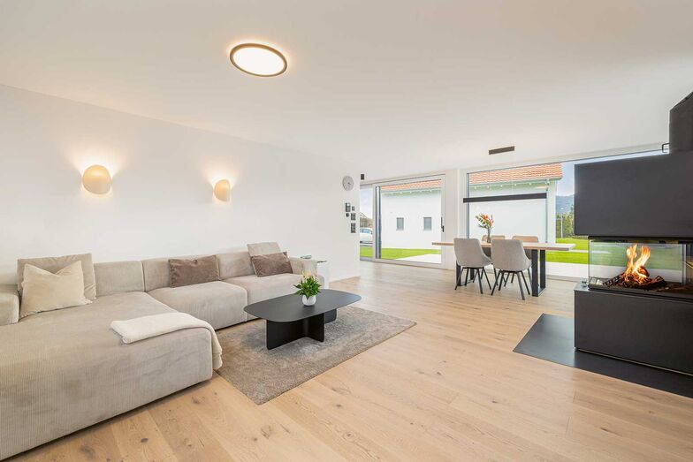 Um das Cheminéefeuer ­gruppieren sich eine gemütliche Sofalandschaft und der einladende Essplatz.