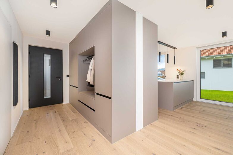 Die Garderobe hat die gleichen grifflosen Fronten wie die Küchenschränke und dient als Windfang für das offen gestaltete Erdgeschoss.
