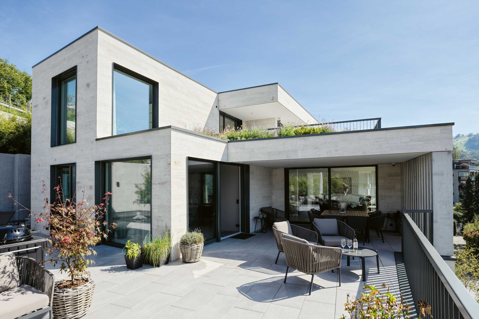 Die weitläufige Terrasse im Wohngeschoss, nach Süden und Westen orientiert, ist in Ess- und Lounge-Zonen unterteilt.