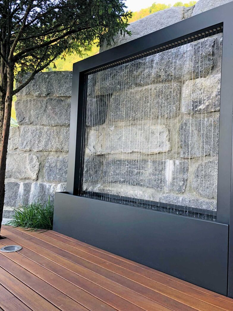 Dieser Aluminiumbrunnen ist ausgestattet mit Chromstahl­seilen und zaubert einen wunderbaren Wasservorhang ohne Geräusche. Im Sommer kühlt das Wasser die Umgebung. Mein Topf GmbH, www.meintopf.ch