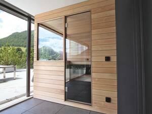Die massgefertigte Sauna von Ging fügt sich präzise in die Loggia ein und nutzt den Platz optimal. Die passgenaue Planung ermöglicht die selbstverständliche Integration in die Architektur. Im Übergang von Innenraum zum Aussenbereich befindet sie sich in einem geschützten Rückzugsort, der dennoch den Blick auf die Landschaft zulässt. Ging Saunabau AG.