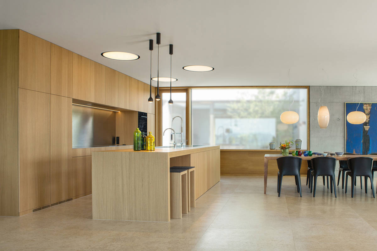 Das helle Eichenholz schenkt der Küche ein warmes Ambiente. Die grosszügige Nische mit Edelstahlrückwand wirkt modern und zeitlos. Elbau.